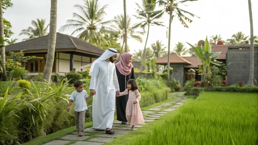 A family walking a path beside rice fields near their villa.
